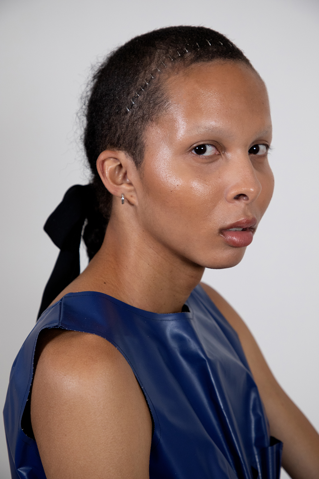 Close up portrait of Valeria with glowing skin looking at the camera against a gray backdrop